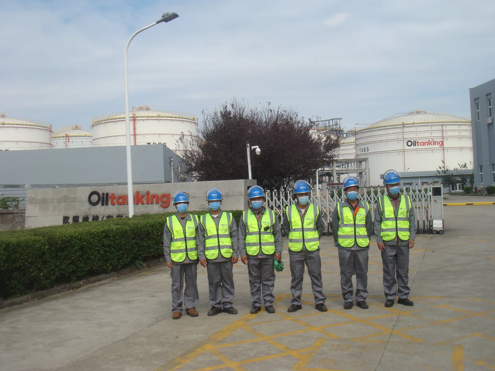Oiltanking project team standing in front of storage tanks at the Qingdao facility.